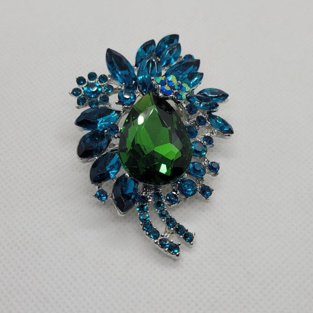 Silver fashion brooch with blue and green crystals